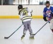 Two young players compete in roller hockey on an indoor rink, showcasing skill and teamwork in their game.