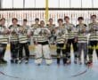 Youth roller hockey team celebrating with medals in front of a goal, showcasing camaraderie and athletic achievement.