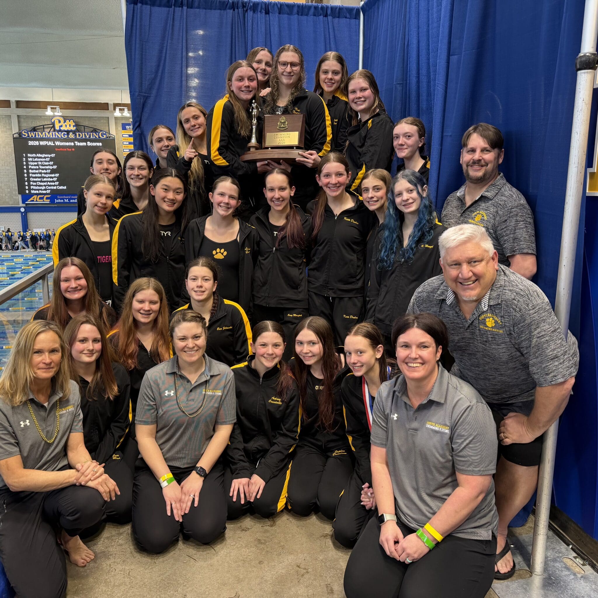 Cheerful team of female swimmers celebrating their trophy win at a swimming competition, showcasing teamwork and achievement.