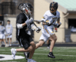 Lacrosse players in action during a game, showcasing athleticism and teamwork on a bright day.