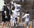 Lacrosse players celebrate a goal, showcasing teamwork and excitement on the field during a sunny game day.