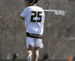 Lacrosse player in action wearing jersey number 25, showcasing teamwork with Brotherhood on display.