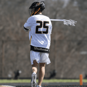 Lacrosse player in action wearing jersey number 25, showcasing teamwork with Brotherhood on display.