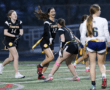 Excited female flag football players celebrating a play during a game on a field, showcasing teamwork and sportsmanship.