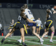 Two female players compete for a pass during a night flag football game, showcasing athleticism and teamwork.