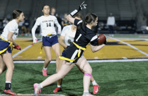 Action shot of female flag football players in a competitive match, showcasing agility and teamwork on the field.