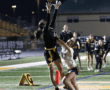 High school girls' flag football game: player leaps to catch a pass while being defended by an opponent. Nighttime action shot.