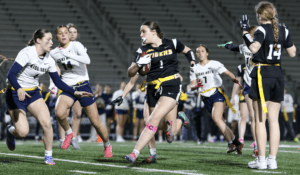 Female flag football players compete fiercely on the field, showcasing athleticism during an exciting game.