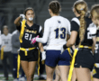 Two female football players engaged in a sports exchange, highlighting teamwork and competition on the field.
