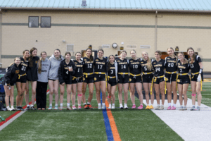 Group photo of the Tigers' female flag football team, celebrating together on the field before a game.