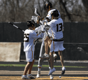 Lacrosse players celebrating a goal on the field, showcasing teamwork and athleticism during a match.