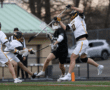 High school lacrosse players compete intensely for the ball during a game on an outdoor field.