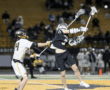 Action-packed lacrosse match featuring a player making a dynamic play while being guarded by an opponent.