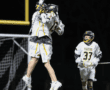Lacrosse players celebrate a goal with an excited jump during a night game on the field. Team spirit in action!