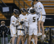 Lacrosse team celebrates a goal, showcasing teamwork and excitement on the field during a night game.