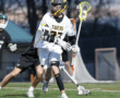 High school lacrosse player in action wearing a Tigers jersey, preparing to pass during an intense game.