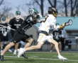 High school lacrosse players compete fiercely, showcasing skill and athleticism during a game action scene.