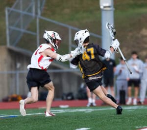 Lacrosse players compete on the field, showcasing athleticism and teamwork during a dynamic game moment.