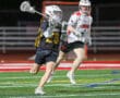 Two lacrosse players compete on a brightly colored field, showcasing athleticism and competitive spirit in a night game.