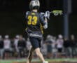 Lacrosse player wearing jersey number 33 passes the ball during a night game, showcasing athletic skill and teamwork.