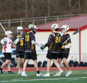 Lacrosse team players celebrating a play, showcasing teamwork and sportsmanship on the field.