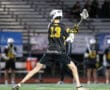 Lacrosse player in action, wearing jersey number 13, preparing to pass the ball on a well-lit field.