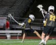 Lacrosse players in action at night, showcasing teamwork and skill on the field during a youth game.