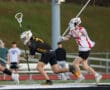 High school lacrosse players compete for the ball on a field, showcasing dynamic action in a competitive game.