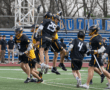 Lacrosse team celebrates a goal on the field, showcasing teamwork and excitement during the match.