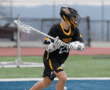 Lacrosse player in black Tigers jersey practicing shots on a field, showcasing athleticism and focus in action.