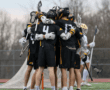Lacrosse team celebrating together on the field, showcasing teamwork and camaraderie during a match.
