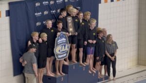 PIAA Champions swim team celebrating victory with trophy and banner at a poolside awards ceremony.