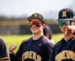 Baseball players celebrating on the field, wearing black and gold uniforms, showcasing team spirit and camaraderie.