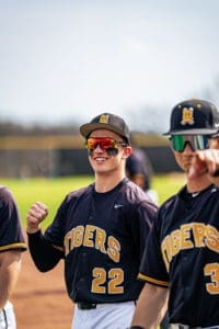 Baseball players celebrating on the field, wearing black and gold uniforms, showcasing team spirit and camaraderie.
