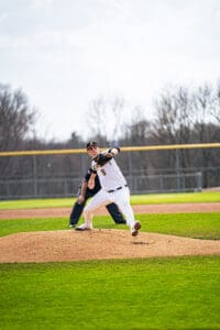 A baseball pitcher in a striped uniform winds up for a throw on a sunny day at the ballpark.