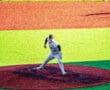 A baseball pitcher on the mound prepares to throw against a vibrant field background. Bright colors enhance the scene.