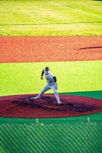 A baseball pitcher on the mound prepares to throw against a vibrant field background. Bright colors enhance the scene.