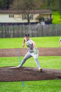 Young baseball pitcher in motion on the mound, showcasing intense focus during a game on a vibrant field.