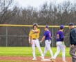 Baseball players in uniforms celebrate on the field during a game, showcasing teamwork and excitement.