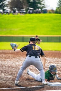 Baseball player slides into base while opposing player prepares to tag, capturing a thrilling moment on the field.
