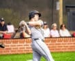 Baseball player swinging a bat during a game, with spectators in the background enjoying the action.