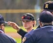 Young baseball player engaging in conversation with umpires during a game, showcasing teamwork and sportsmanship.