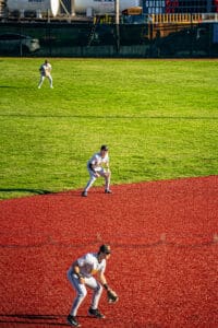 Three baseball players positioned on a vibrant field, focused on the game as they prepare for action.