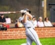 A baseball player swings a bat on the field, aiming to hit a pitch during a game with spectators in the background.