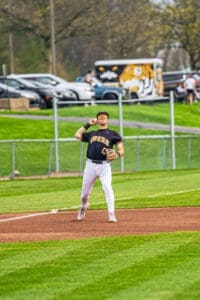 Baseball player in black Tigers uniform preparing to catch a fly ball on a sunny day at the diamond.