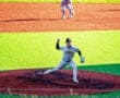 A baseball pitcher from the Tigers team prepares to throw a pitch, with a player in position on the field.