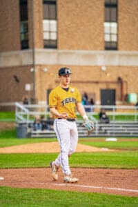 College baseball player in a yellow Tigers jersey prepares on the field, showcasing athleticism and team spirit.