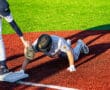 A baseball player hand slides into base while another player reaches for him, showcasing an intense moment on the field.