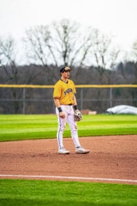 Player in a yellow Tigers jersey stands on the baseball diamond, ready for action during a game.