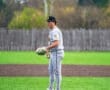 Young baseball pitcher on the mound, focused and ready to throw, with a vibrant green field in the background.